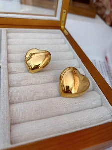 Detailed view of polished 18K gold-plated heart earrings displayed in a luxury jewelry box