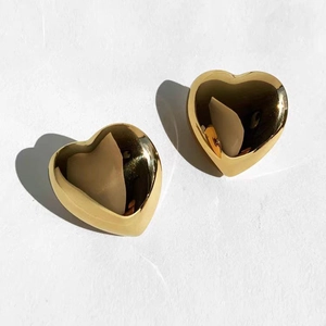 Macro view of mirror-polished gold heart earrings with elegant light and shadow effects