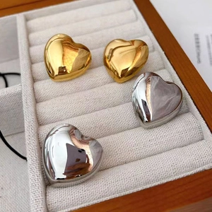 Detail of polished heart-shaped stud earrings in gold and silver finish on a display tray