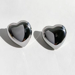 Macro view of minimalist silver heart studs with high-polish metallic finish for women