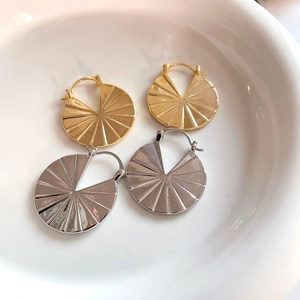 Macro detail of geometric fan-shaped earrings in polished gold and silver plated metal
