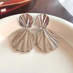 Irregular silver geometric fan-shaped earrings with pleated metallic texture on white plate