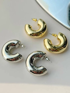Detail of chunky C-shape hoop earrings in polished gold and silver finishes