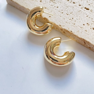 Detailed view of polished 18K gold-plated thick C-shaped hoop earrings on stone