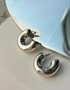 Macro shot of silver chunky C-shaped hoop earrings with a high-polished metallic finish