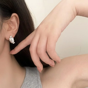 Minimalist silver knot earrings in high-polished metal finish worn by a model