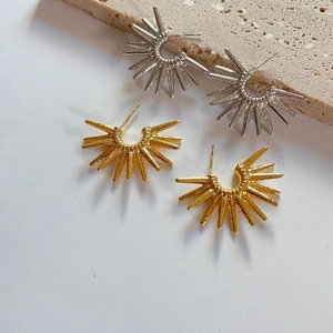 Detailed close-up of sunburst spike earrings in polished gold and silver metallic finishes