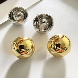 Détail de grandes boucles d'oreilles sphériques dorées et argentées avec fini miroir poli