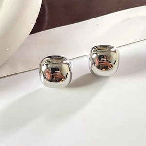Détail macro de boucles d'oreilles carrées argentées avec finition polie miroir