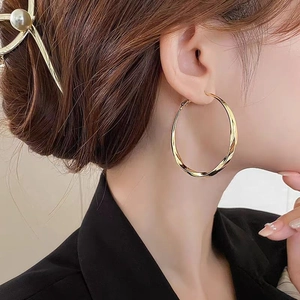 Fashionable oversized gold twisted hoop earring for women with polished spiral texture