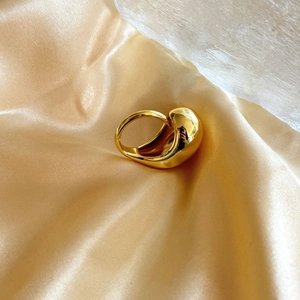 Macro shot of 18K gold plated teardrop ring on elegant satin fabric background