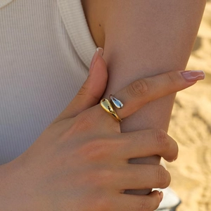 Close-up of adjustable open ring featuring gold and silver teardrop metallic design