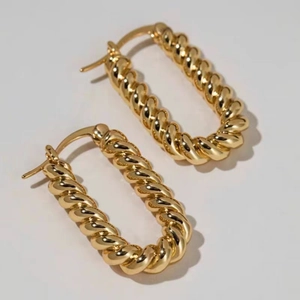 Close-up of golden twisted rope texture on oval hoop earrings with polished finish