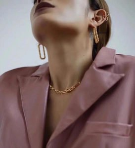 Detailed close-up of golden chunky chain link earrings and necklace set on a female model