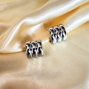 Minimalist silver wide C-shape ridged metal earrings on elegant gold satin background