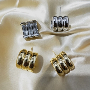 Detailed close-up of C-shaped geometric earrings with textured metallic finish in gold and silver