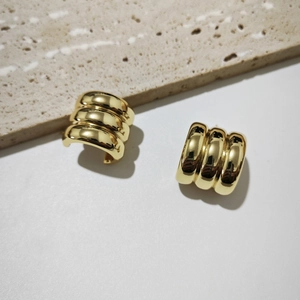 Detailed view of gold C-shaped chunky hoop earrings with vertical ribbed texture and finish