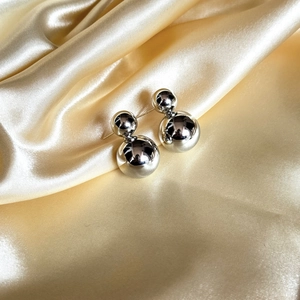 Boucles d'oreilles double boule en argent poli sur tissu en soie dorée luxueux