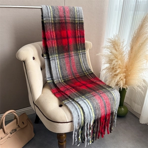 Detailed view of red and yellow plaid scarf with fringe on a beige sofa chair