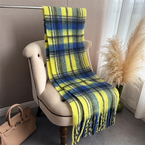 Detail shot of yellow and blue plaid cashmere-like scarf with long fringe on a chair