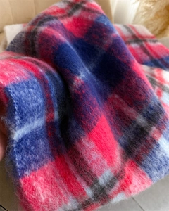 Close-up of soft rainbow plaid mohair fabric with brushed texture and vibrant tassels
