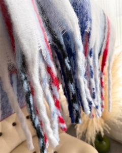 Macro detail of rainbow plaid mohair scarf with thick braided tassels and soft texture