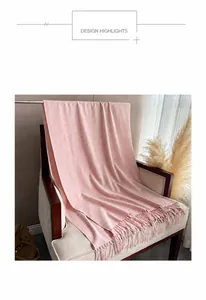 Dettaglio di sciarpa pied de poule rosa e bianca con frange su una poltrona
