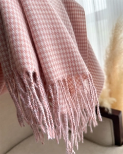 Dettaglio di una sciarpa a quadri rosa e bianchi con eleganti frange alle estremità