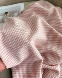 Dettaglio ravvicinato del morbido tessuto pied de poule rosa e bianco con texture fine