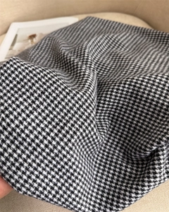 Vista ravvicinata del tessuto cashmere pied-de-poule bianco e nero con dettagli frange