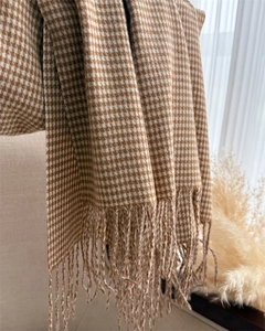 Primo piano di una raffinata sciarpa in finto cashmere con motivo pied-de-poule e frange.