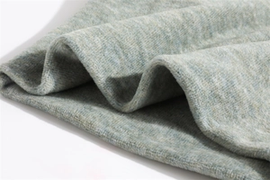 Close-up of soft knitted light gray-green fabric with thick texture and fuzzy surface