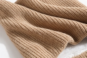 Macro shot of warm camel knit fabric with thick white faux sherpa fleece lining
