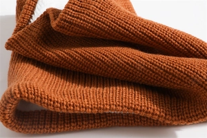 Macro shot of rust red ribbed knit fabric texture showing thick warm thermal material