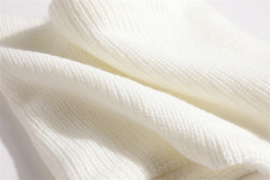 Macro detail of soft white ribbed knit fabric texture with thick warm fiber weave