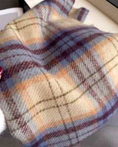 Dettaglio del tessuto morbido della sciarpa a quadri beige, blu e viola in finto cashmere