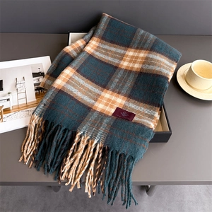 Dettaglio di sciarpa in cashmere a quadri con lunghe nappe ed etichetta in scatola regalo
