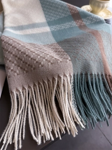 Detail of plaid cashmere-like scarf with soft texture and elegant long tassels