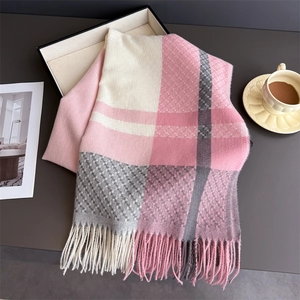Close-up of soft plaid scarf texture with pink and grey tassels on a lifestyle tray
