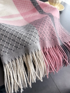 Close-up of pink and grey plaid cashmere scarf with soft fringe and knit texture