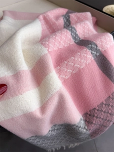 Close-up of soft plaid scarf showing pink and grey knit texture with fringe detail