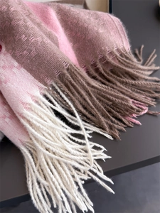 Close-up of pink and brown plaid cashmere-like scarf showing soft texture and tassels