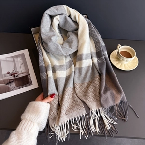Close-up of thick winter scarf with grey plaid pattern and soft decorative fringe