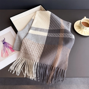 Detailed close-up of thick plaid cashmere feel scarf with long fringes and soft texture