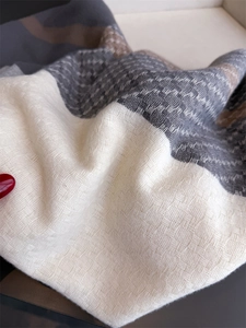 Close-up of thick knit plaid scarf fabric showing detailed texture and soft tassel trim