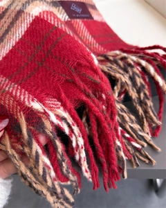 Dettaglio di sciarpa a quadri rossi in finto cashmere con frange lunghe e morbide