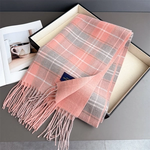 Detail eines weichen Karo-Schals mit Fransen in Geschenkbox mit Lifestyle-Magazin