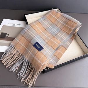Detail eines karierten Schals mit Fransen in einer Geschenkbox mit Elegant-Classic Label