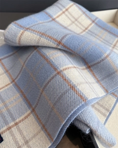 Makroaufnahme der weichen Kaschmir-Textur in Hellblau und Beige mit Fransen-Detail