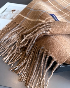 Detailaufnahme der braunen Karoschal-Quasten und weichen Kaschmir-Textur mit blauem Etikett